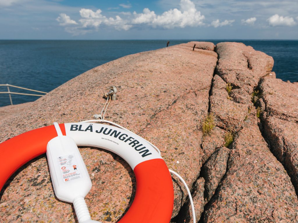 Räddningsboj med texten Blå jungfrun liggandes på en klippa på Blå jungfrun.