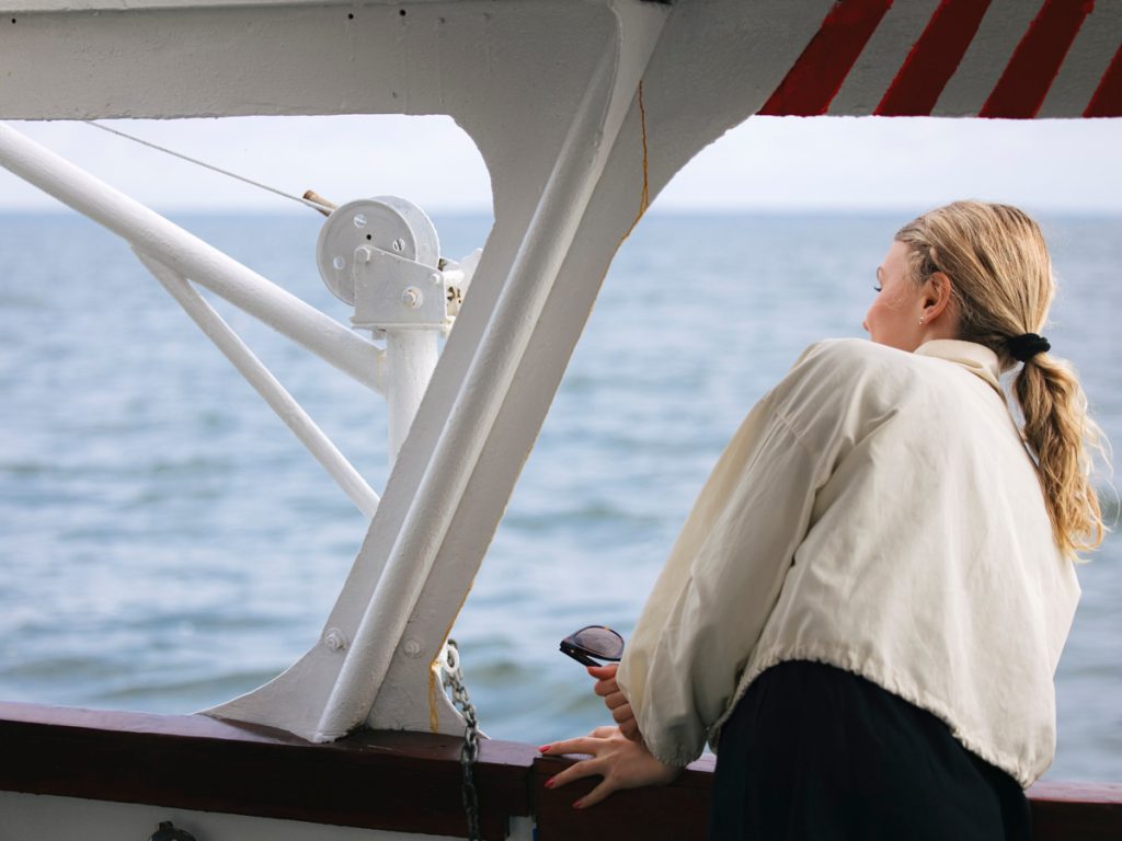 Person som tittar ut från ett fönster på båten M/S Solkust på väg mot Blå jungfrun.