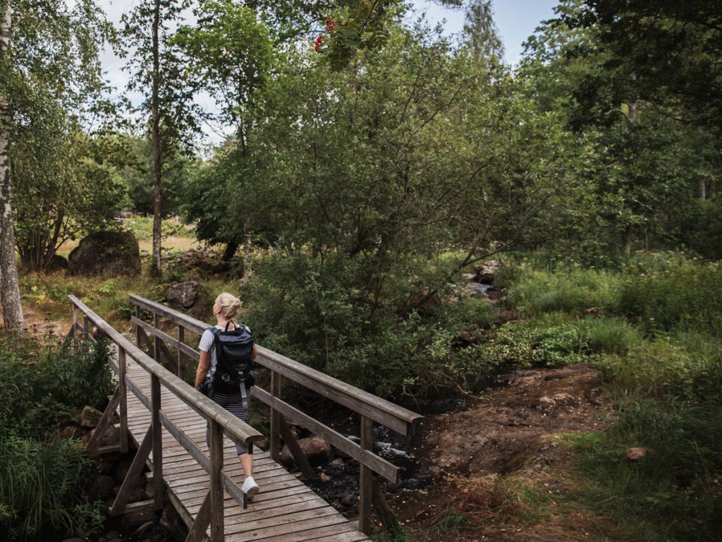 Person som går på en bro genom Kulturreservatet Stensjö by på Ostkustleden i Oskarshamn.