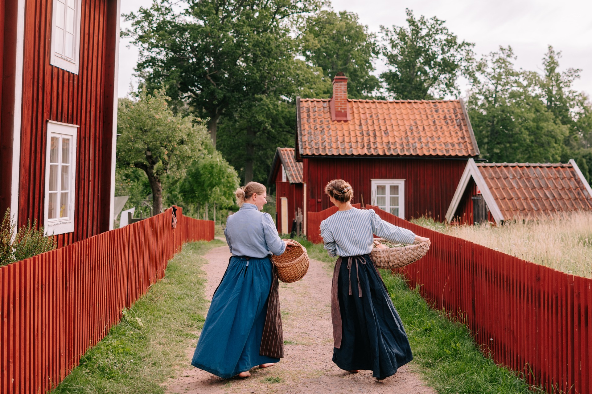 Personer i 1900-talskläder som går i kulturreservatet Stensjö by.