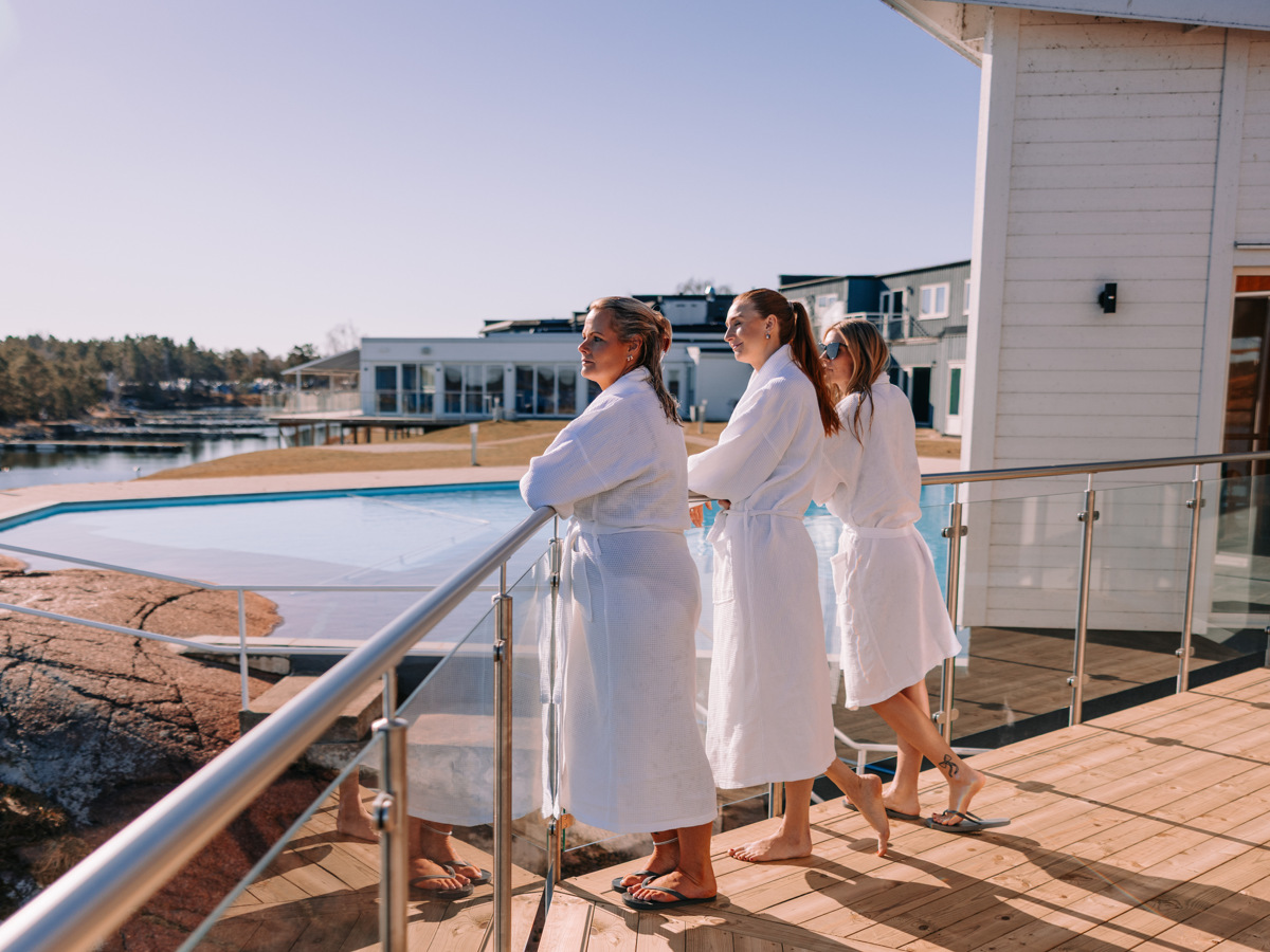 Tre personer som står utanför Relaxen på Hotel Corallen och spanar ut över havet och utomhuspoolen.