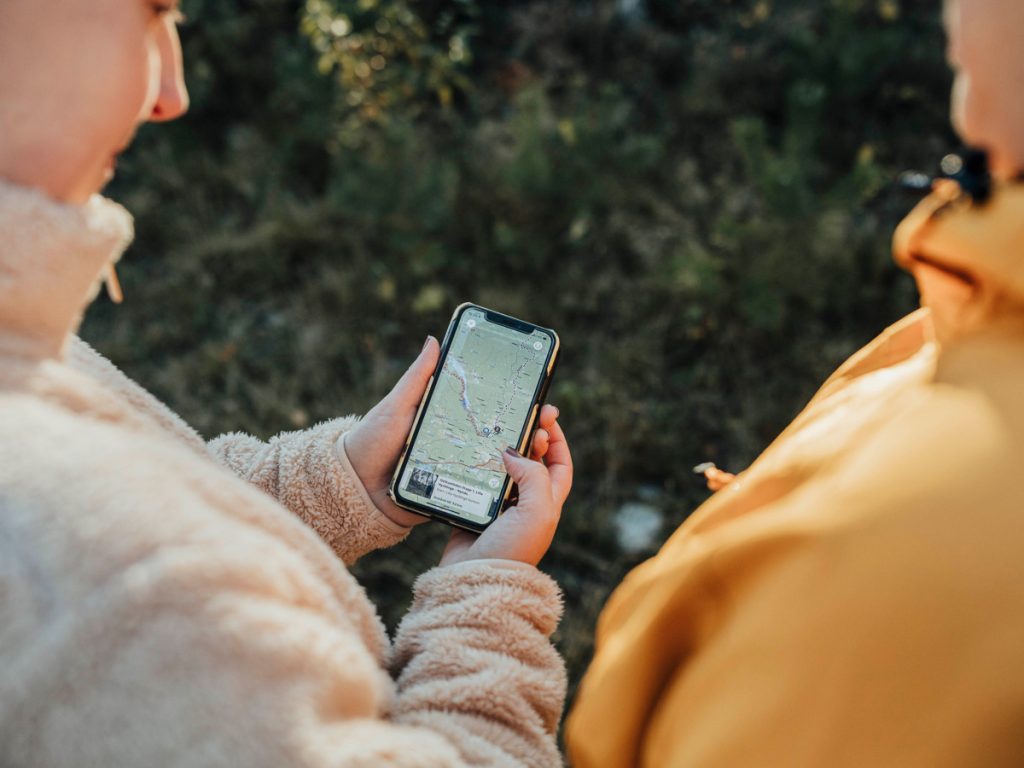 Två personer som tittar i en telefon med appen Naturkartan framme.