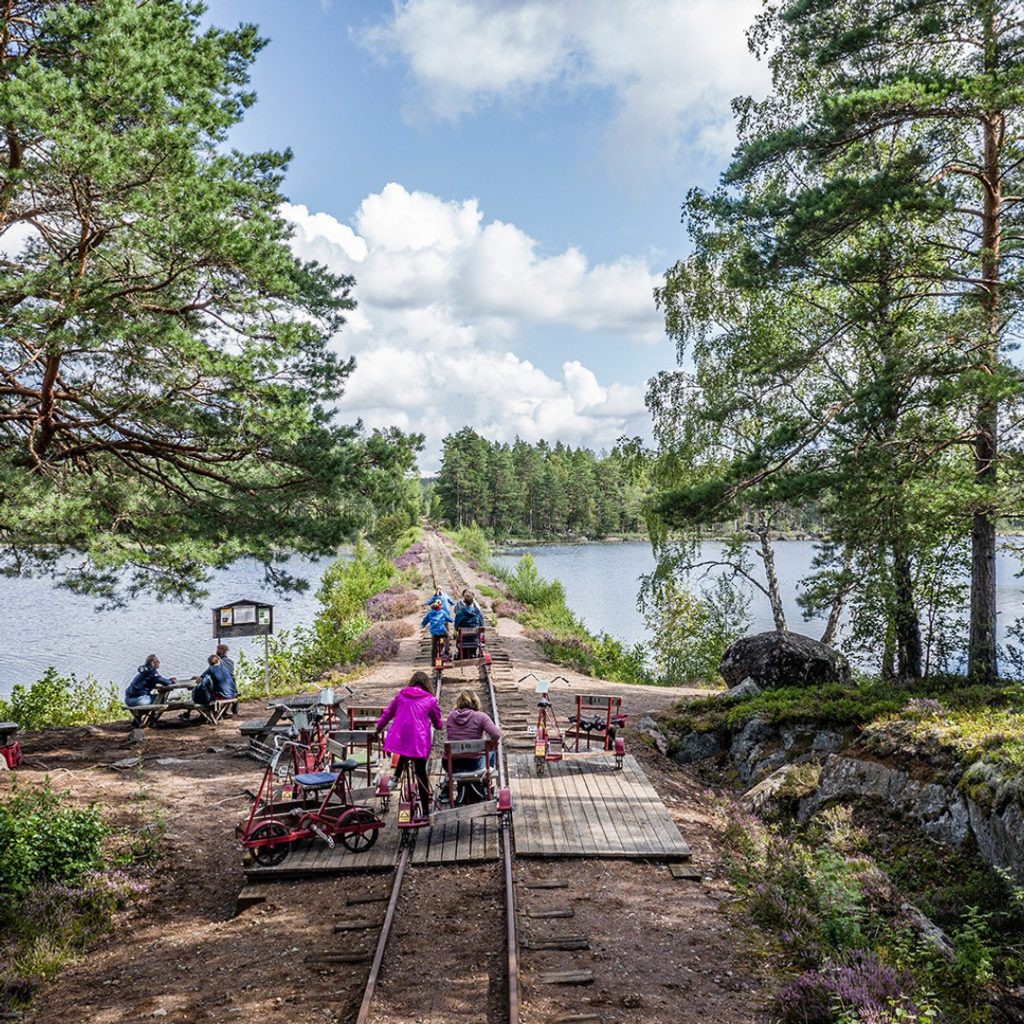 Flera grupper av människor cyklar dressin längs smalspåret i Hultsfred.