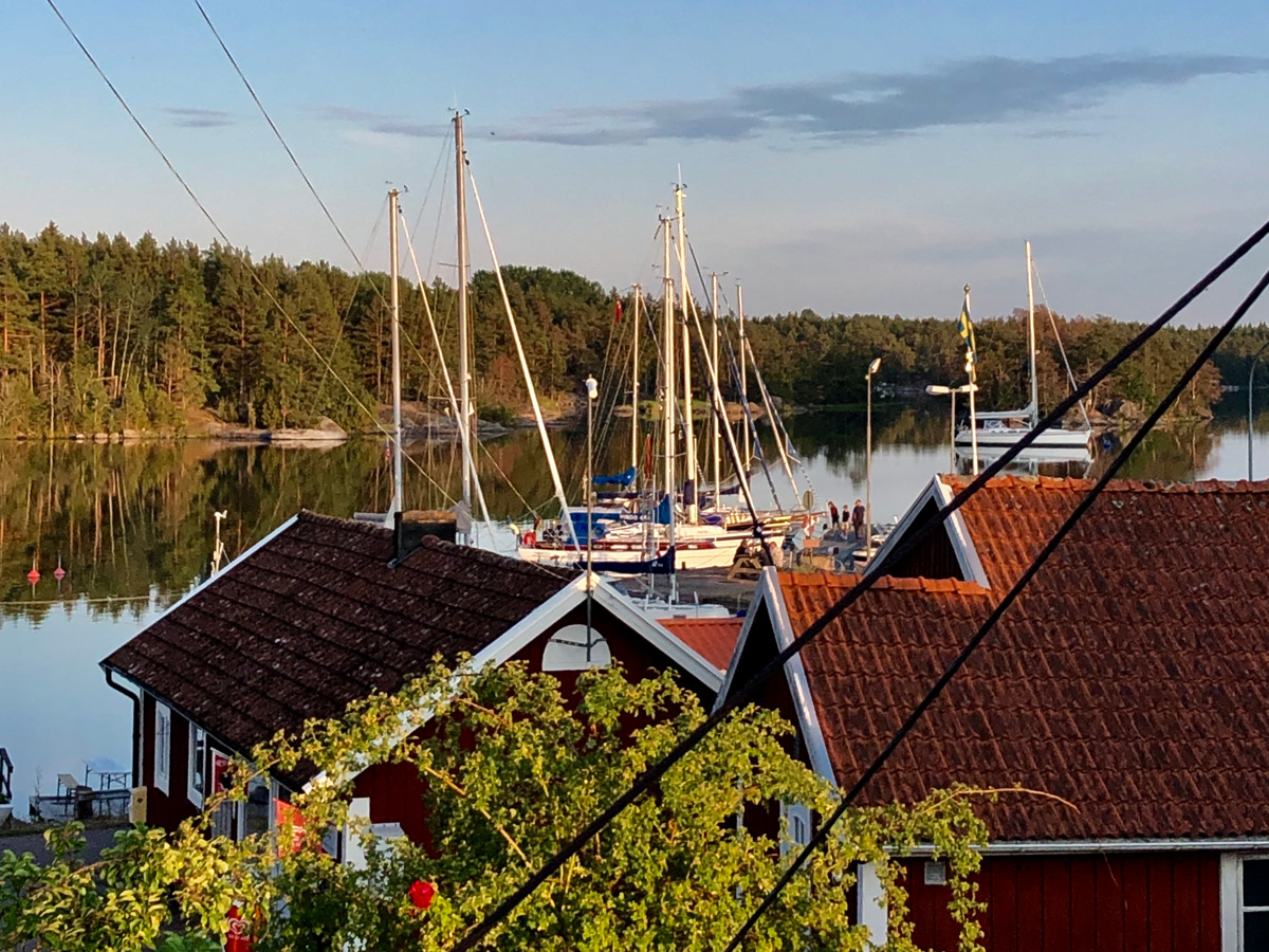 Bild över vackra röda hus, havet i bakgrunden samt segelbåtar i Klintemåla, Oskarshamn.