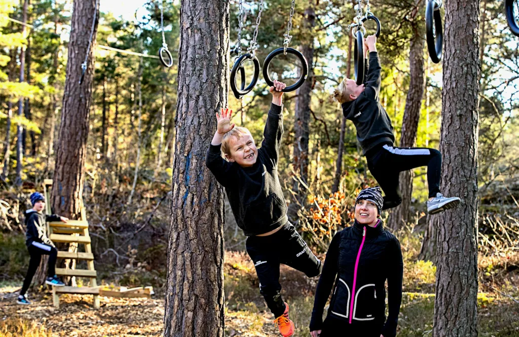 Barn som klättrar i en hinderbana i skogen
