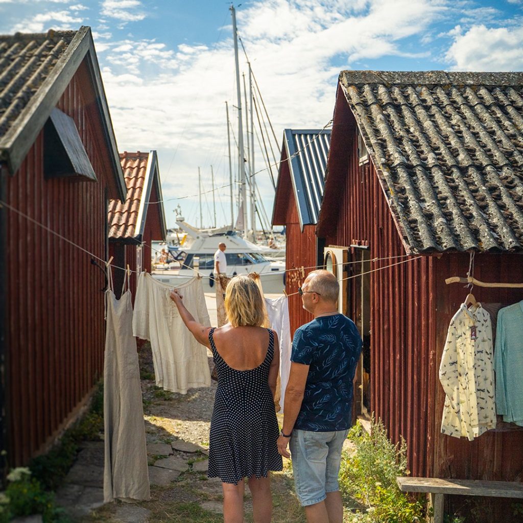 Ett par hänger tvätt mellan röda hamnstugor i Byxelkrok på Öland.