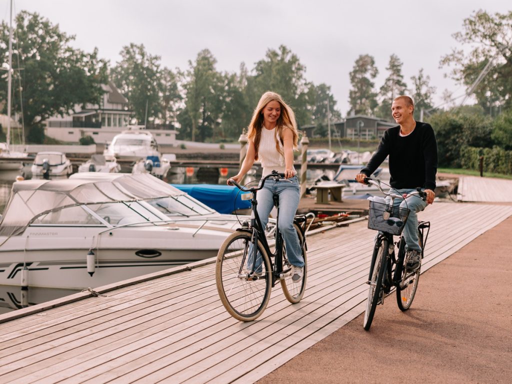Personer som cyklar intill en båthamn.