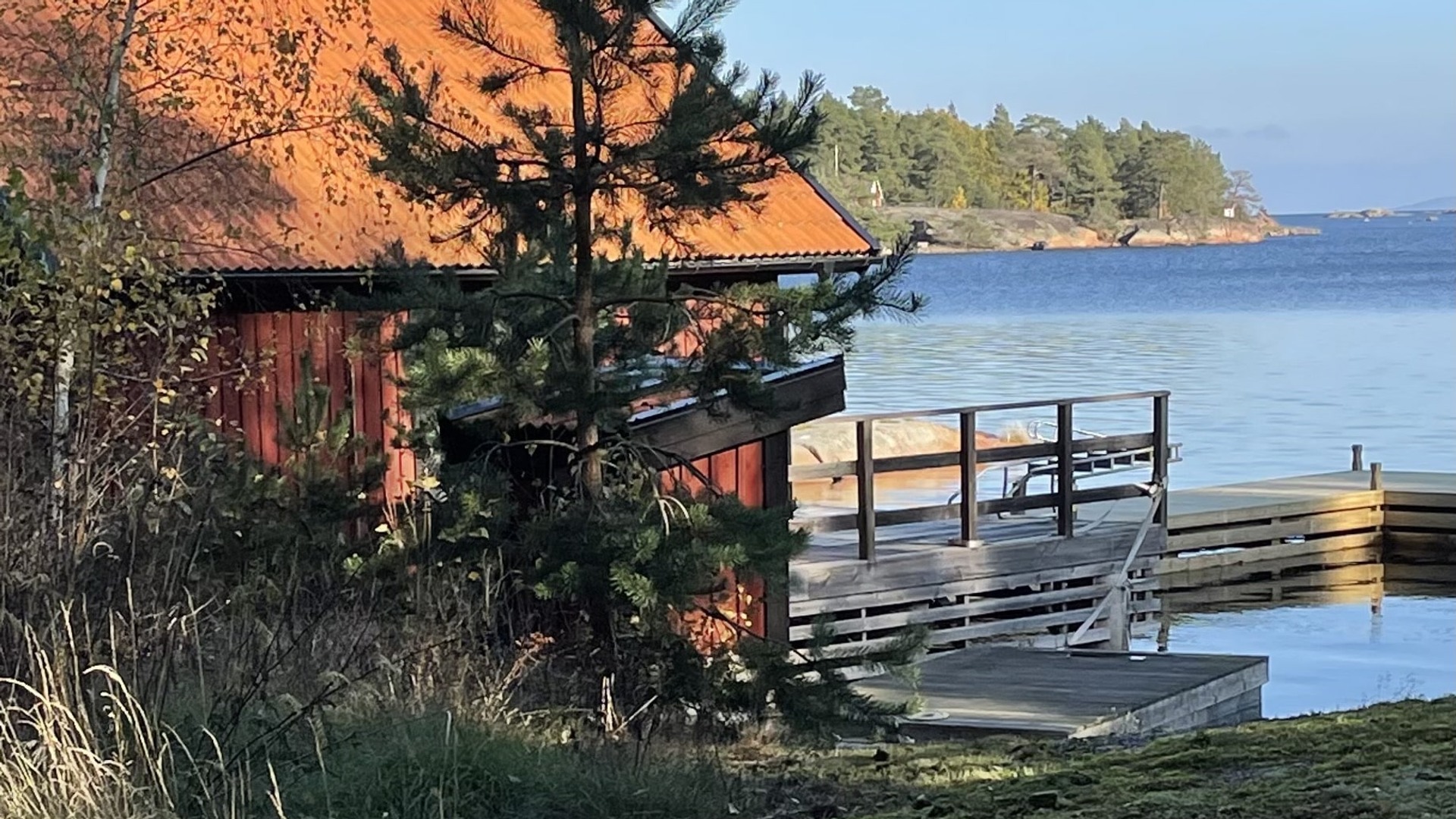 Bild på rött hus och brygga. Våneviks Eremitplats i Oskarshamn.