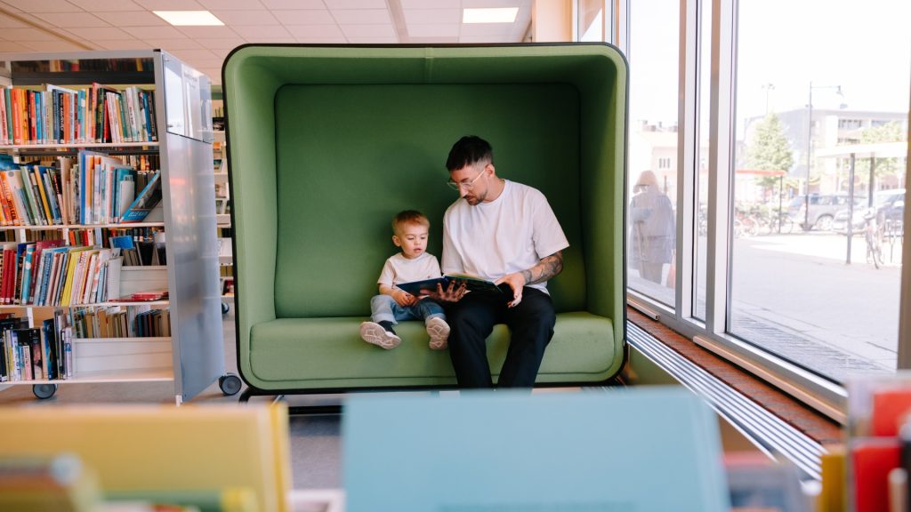 Person som läser för barn i soffa på stadsbiblioteket i Oskarshamn