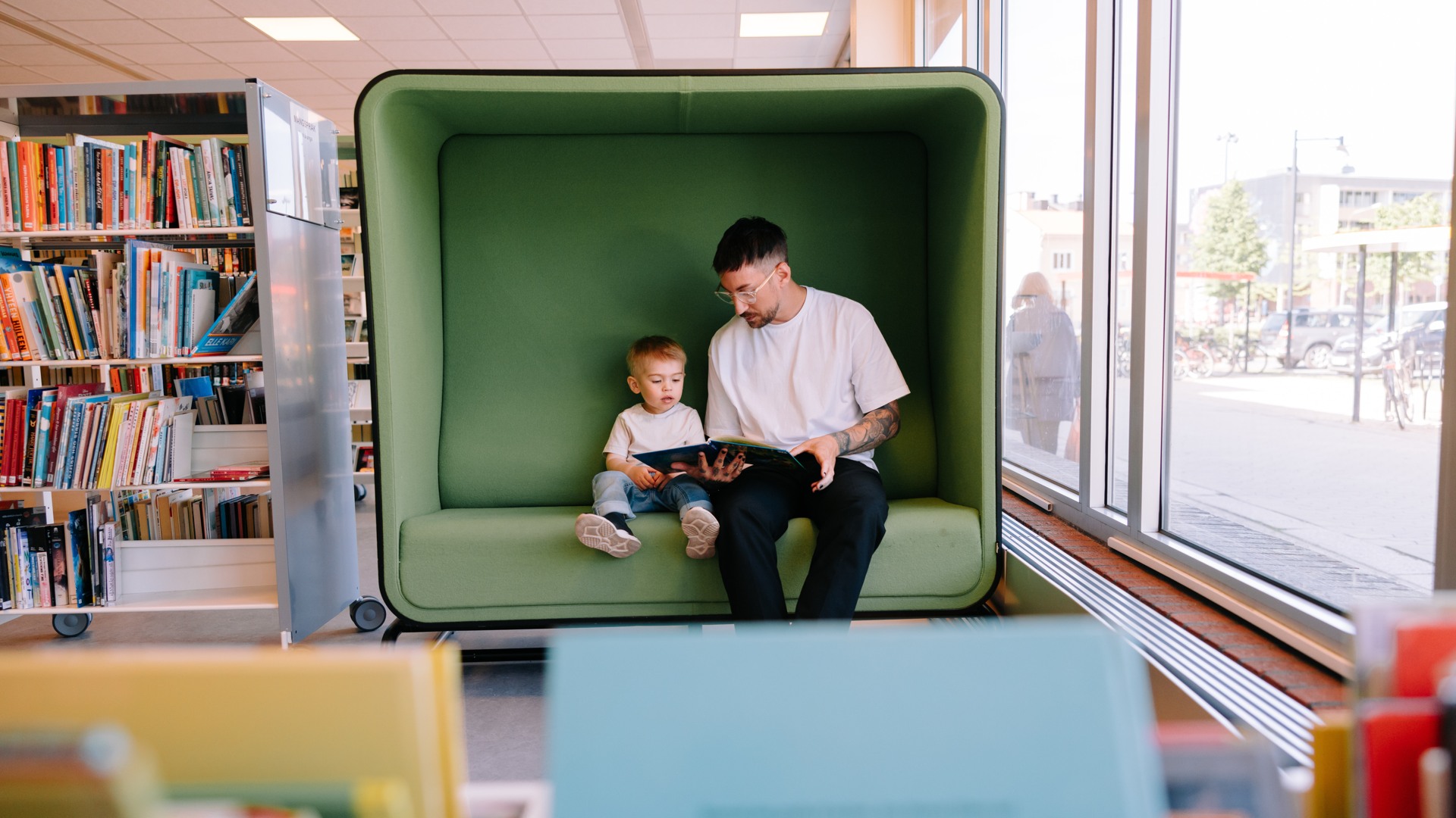 Person som läser för barn i soffa på stadsbiblioteket i Oskarshamn