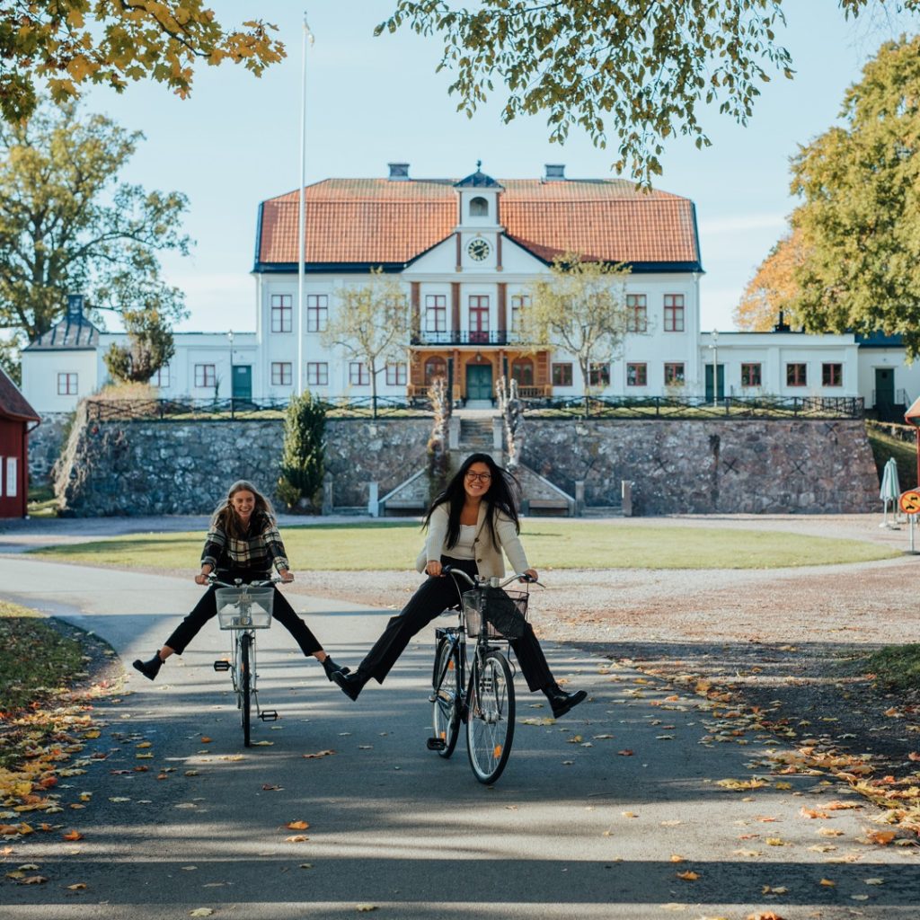 Två personer som cyklar framför Fredriksbergs Herrgård.