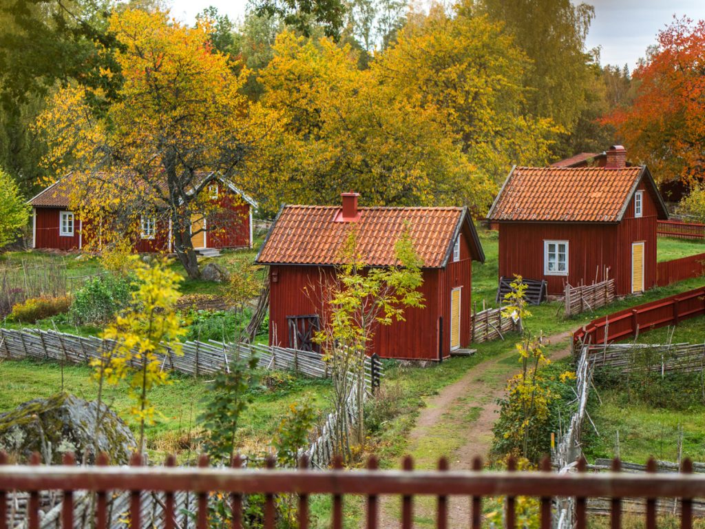 Utsiktsbild över de röda husen i Stensjö by på med höstfärgade träd.
