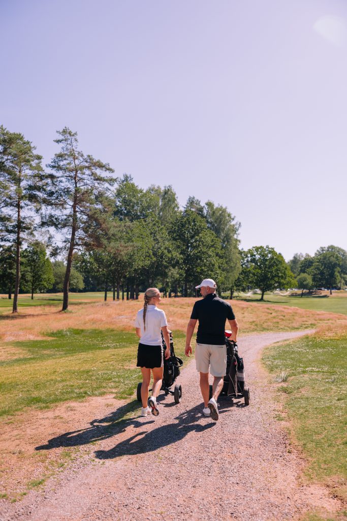 Man och kvinna på golfbana i solen