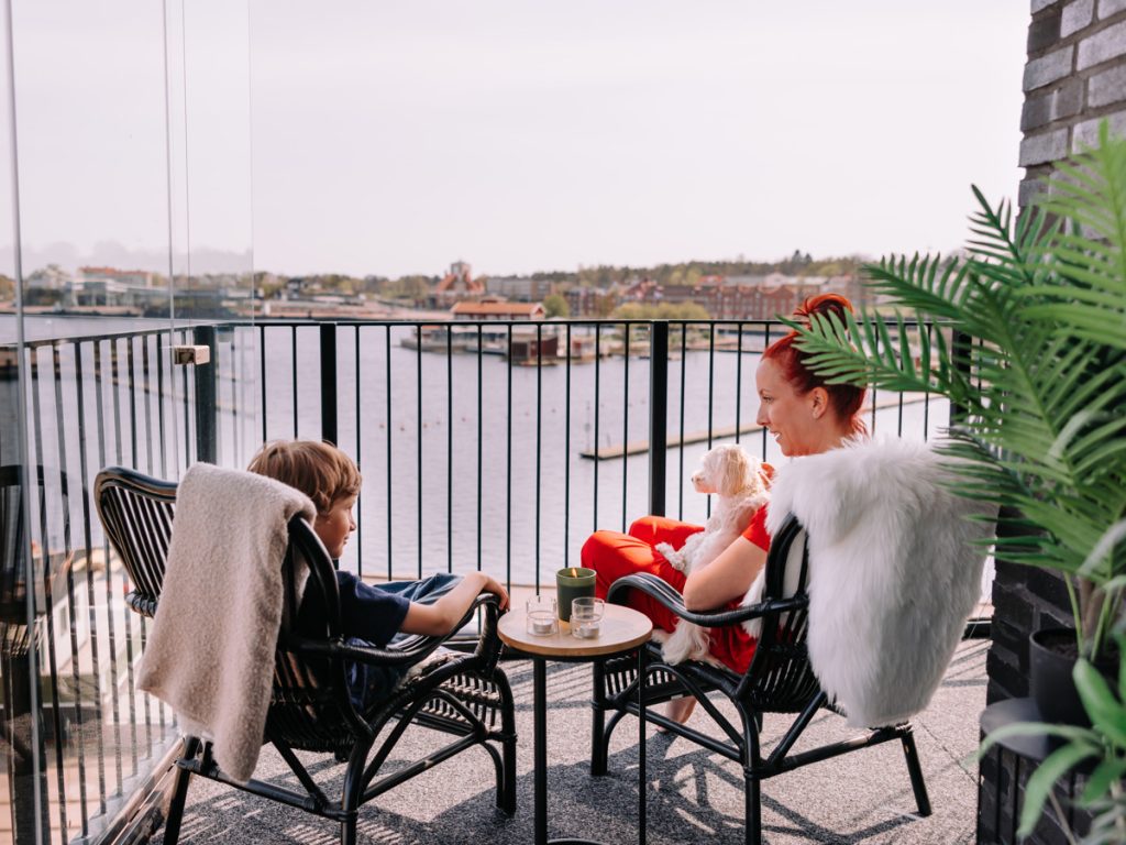 Personer på balkong i lägenhet i Oskarshamn. Norra kajen. Fotograf Cornelia Höglind.
