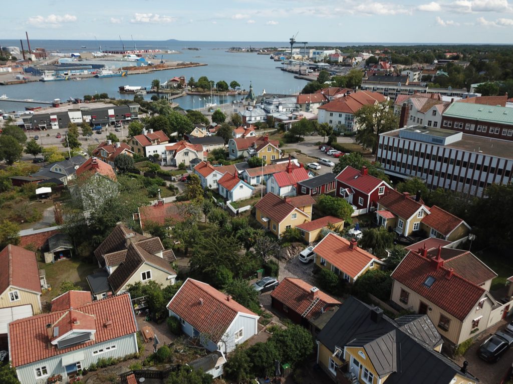 Drönarbild över hustak i Oskarshamn med utsikt över havet.