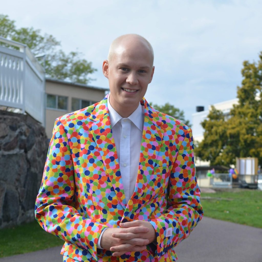 Simon Nord står leende i Stadsparken i Oskarshamn iklädd en prickig, färgglad kavaj.