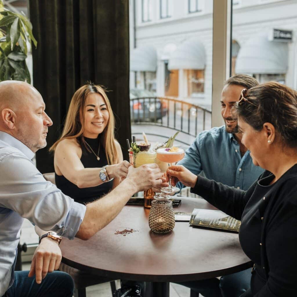 Fyra personer som skålar med drinkar runt ett runt bord på en restaurang i Oskarshamn.